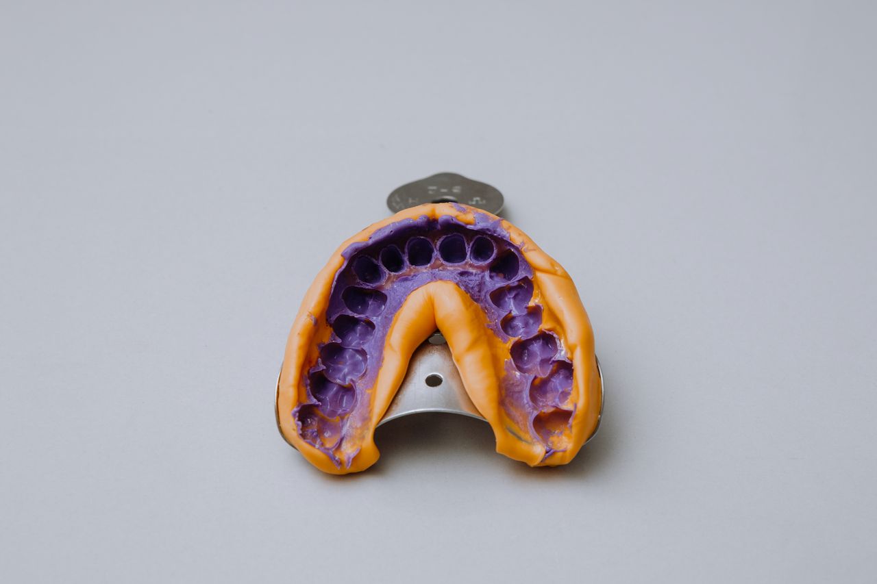 Top view of close up of metal dental impression tray with alginate impression on it placed on white background